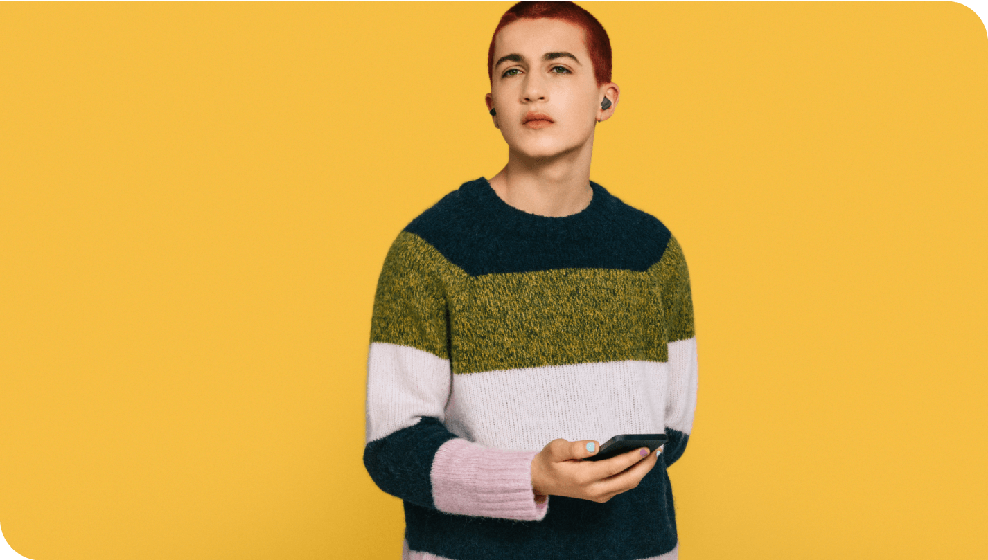 a young person holding a mobile device against a yellow background